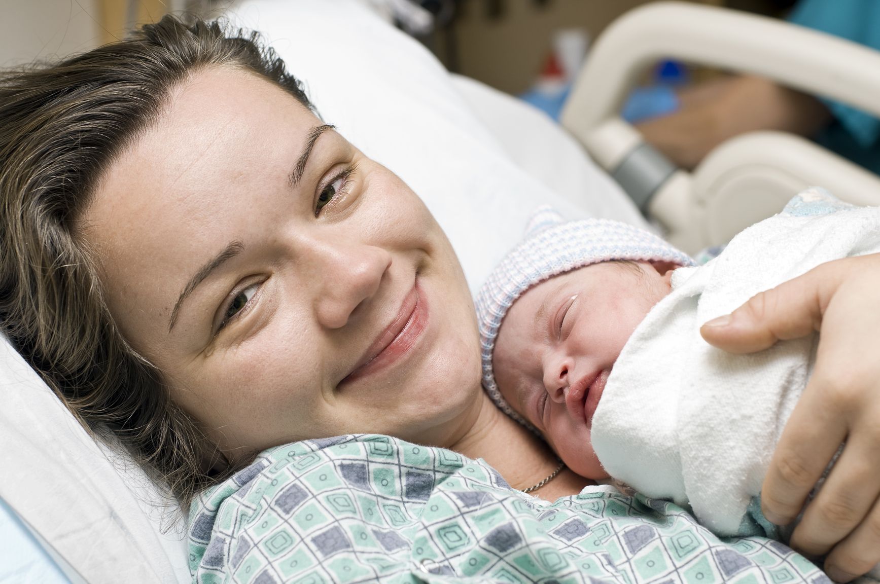 Woman smiling holding her newborn baby after hiring a St Petersburg doula